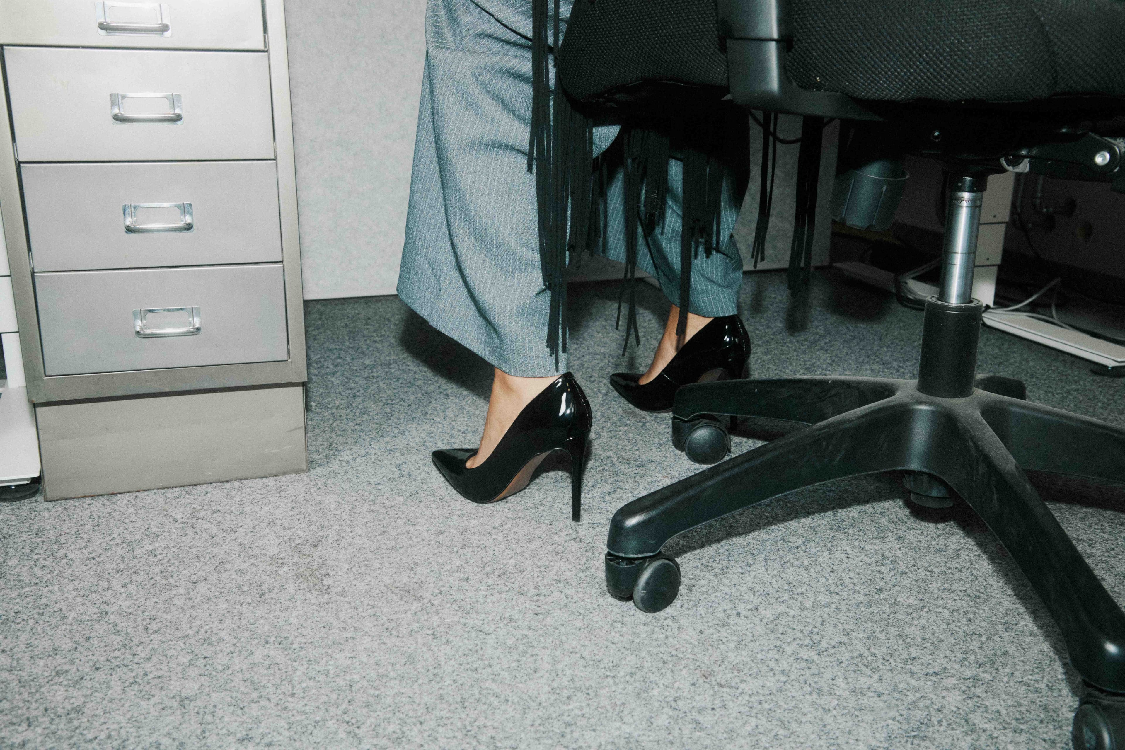 A low-angle of heels beside a filing cabinet.