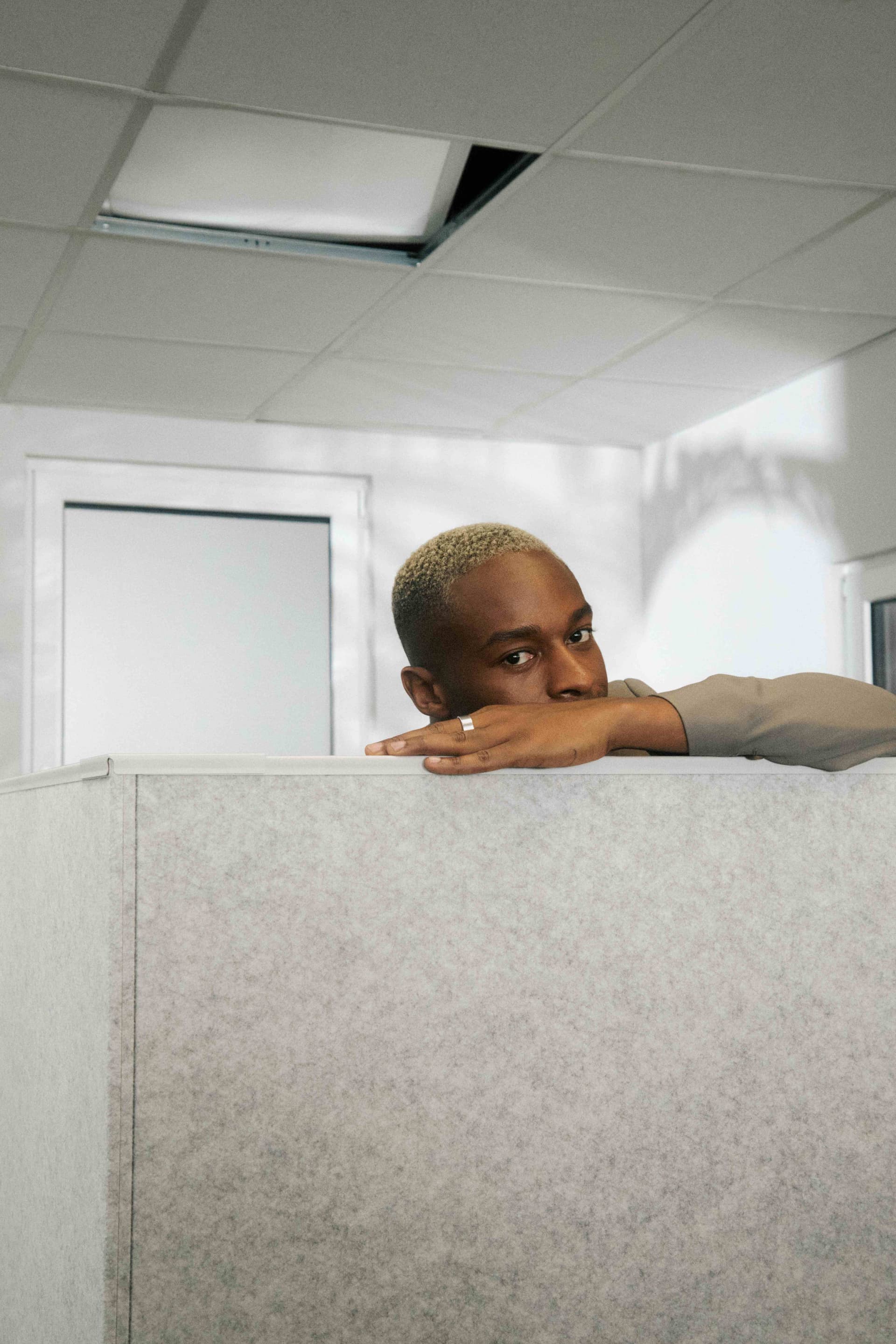 A colleague resting on a cubicle partition, pensive.