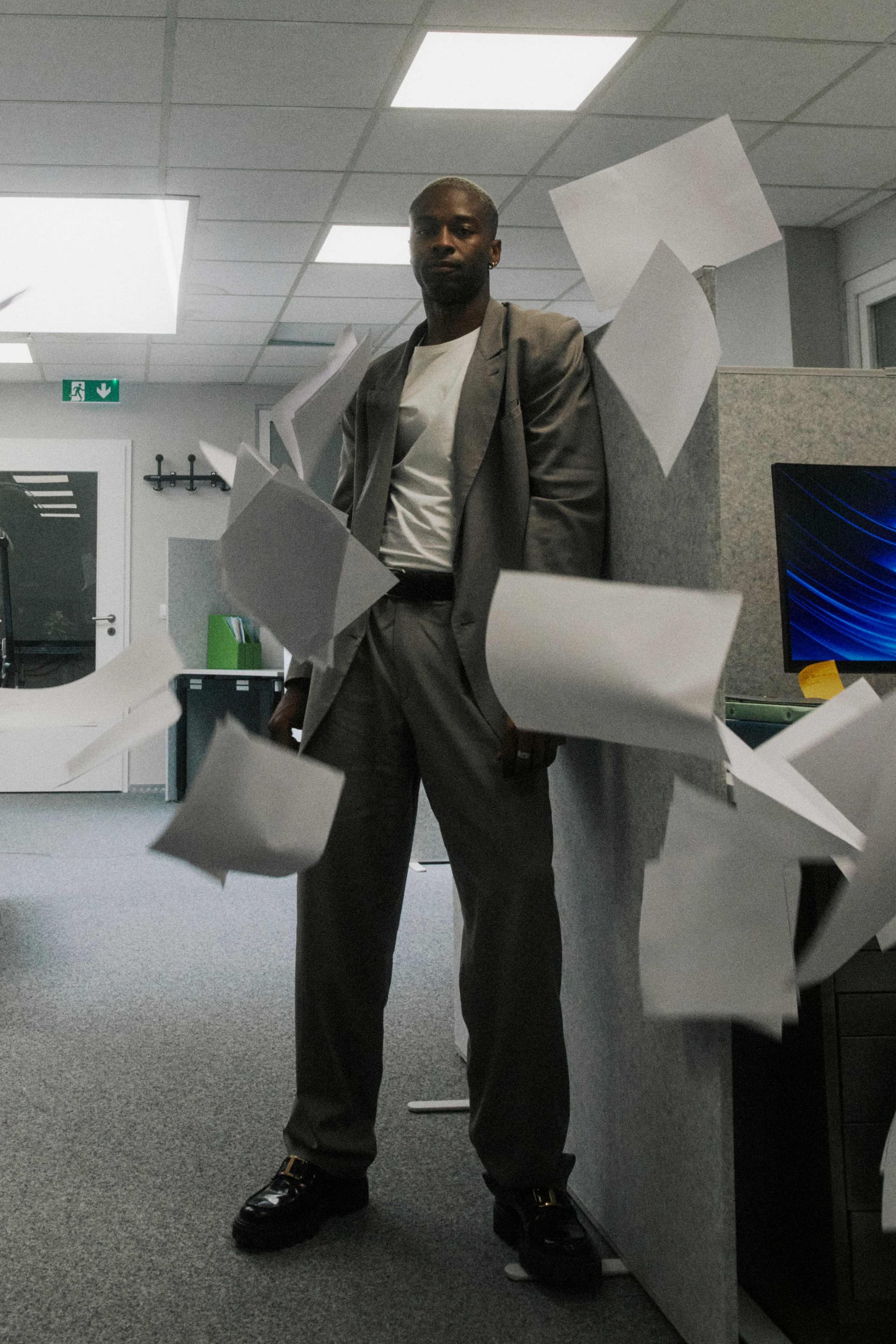 A man in a grey suit composed amid flying papers.
