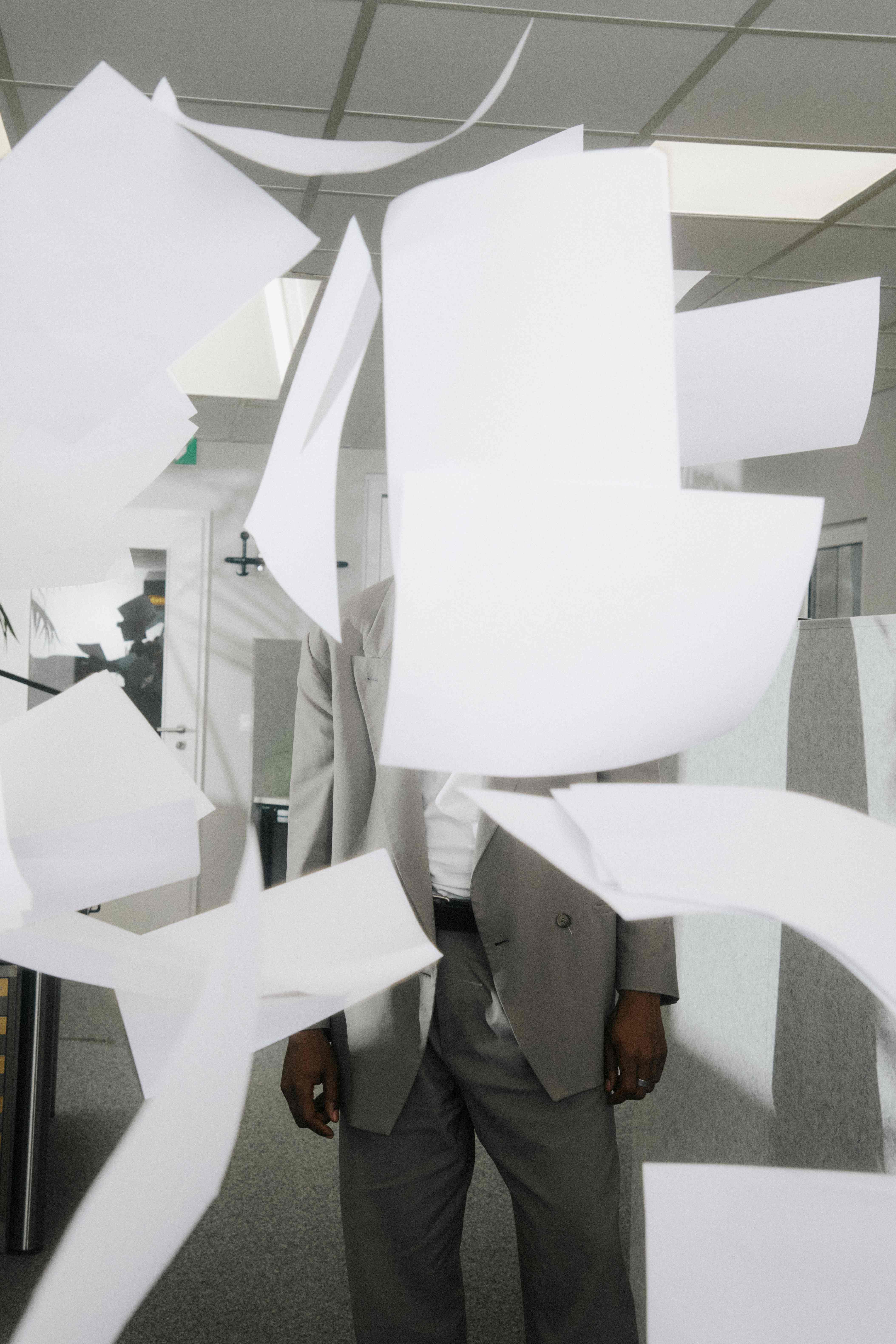 A man's face obscured by flying sheets of paper.