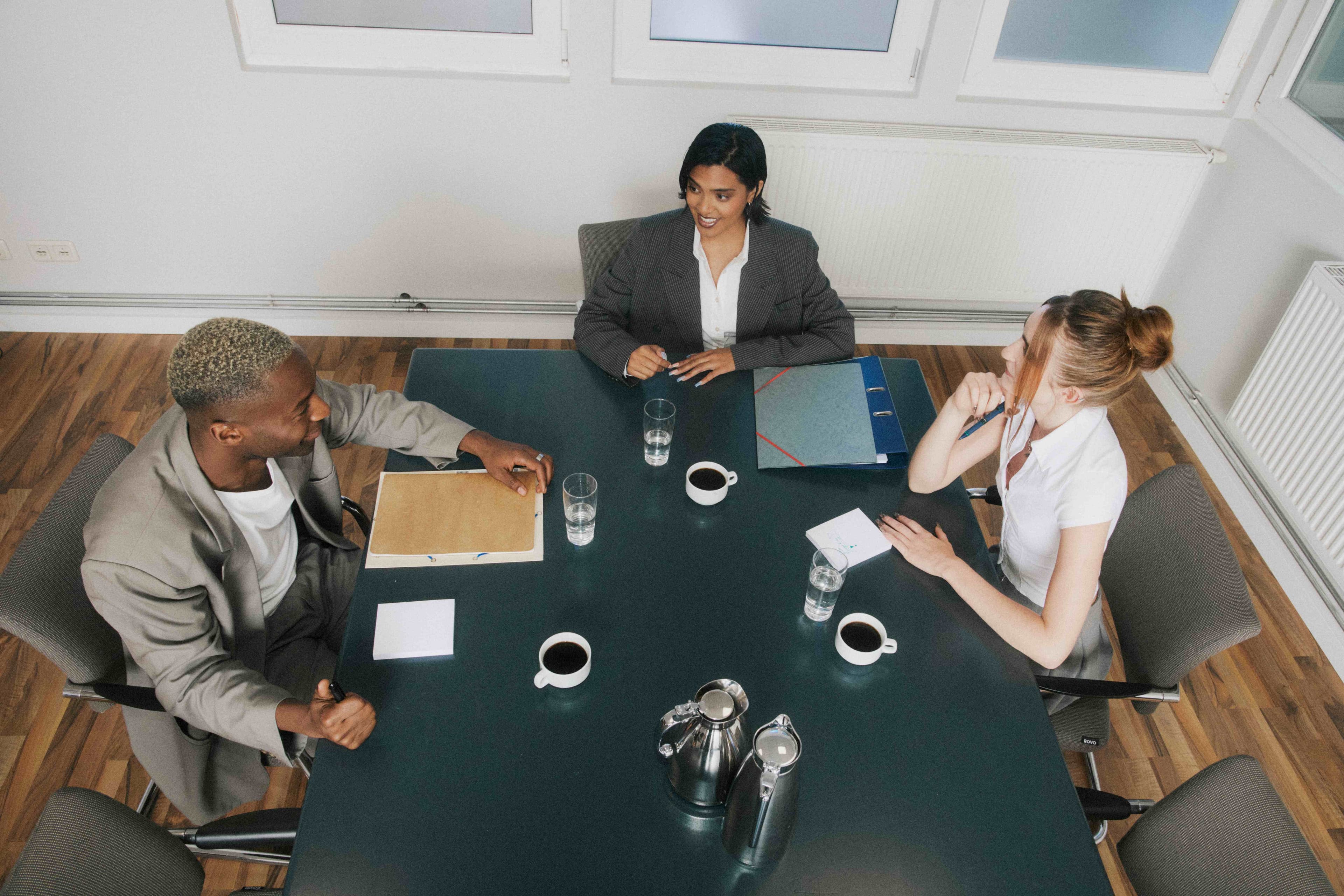 Overhead boardroom with coffee, water, and folders.